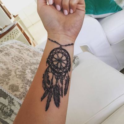  Tatouage attrape rêve soutenu par un bracelet sur l'avant bras